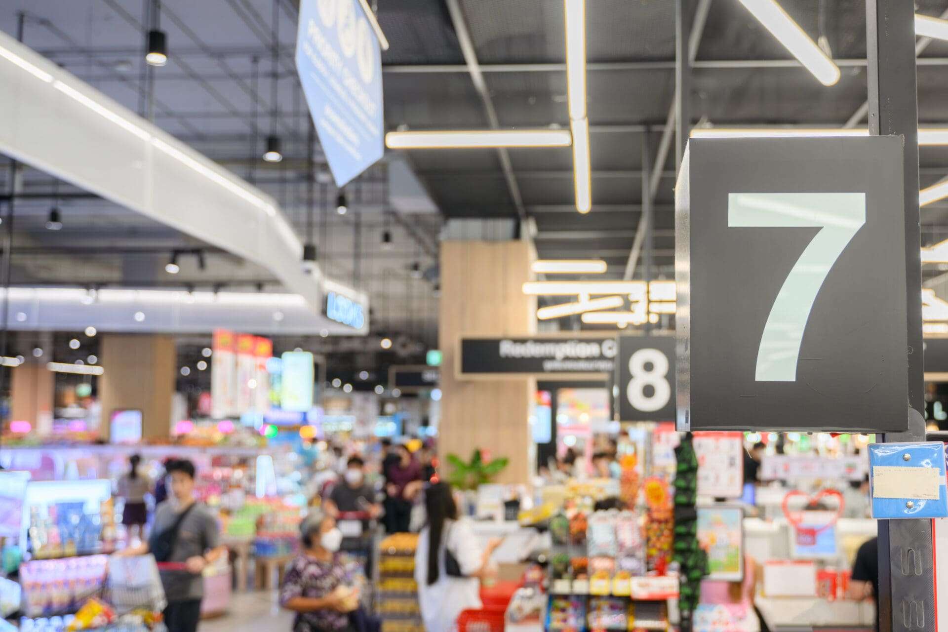 Young woman using phone in grocery store and looking grocery list.